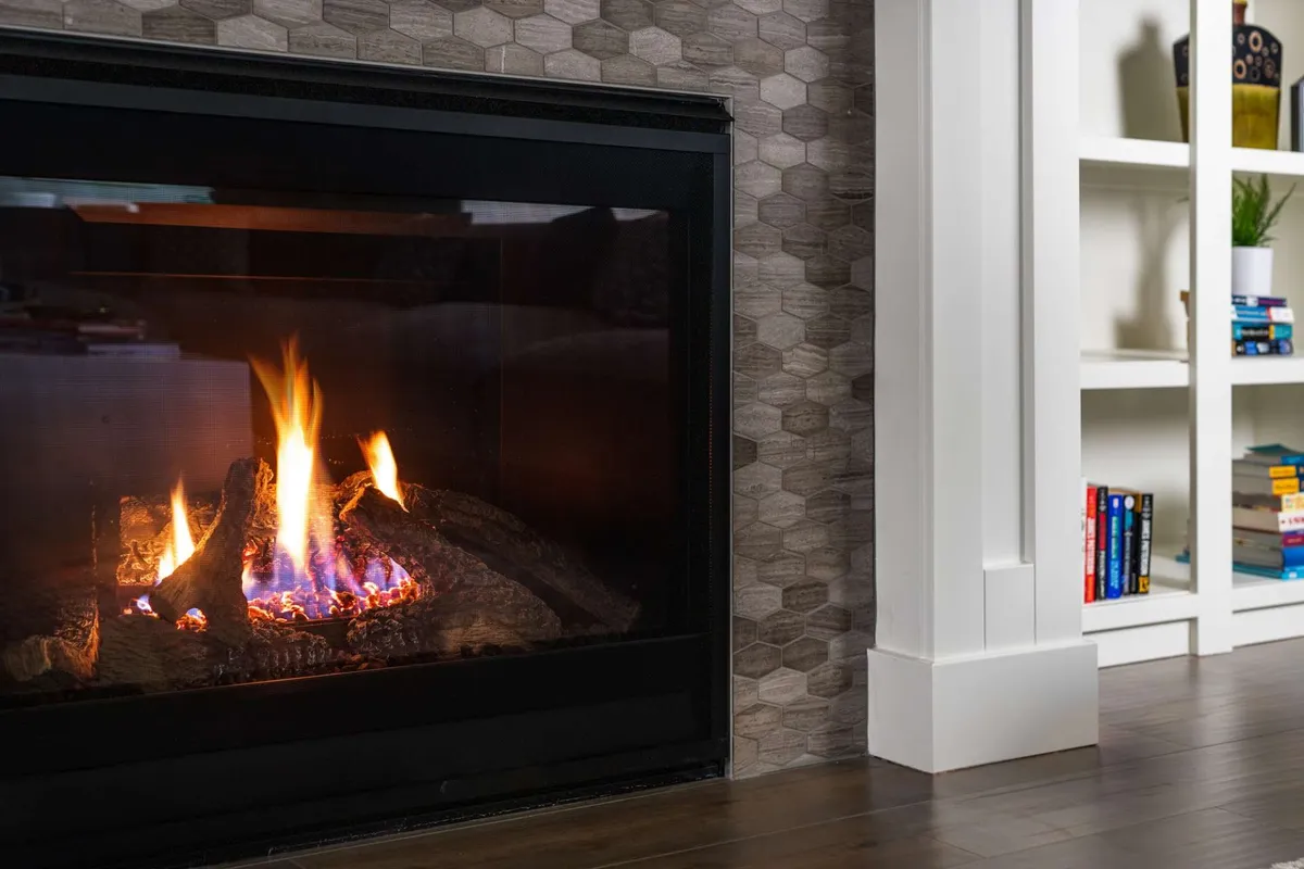 A shared living space centered around a warm fireplace, complemented by a hexagonal tile wall and a bookshelf. The setting is perfect for intimate gatherings, family games, or reading by the fire, exuding warmth and connection.