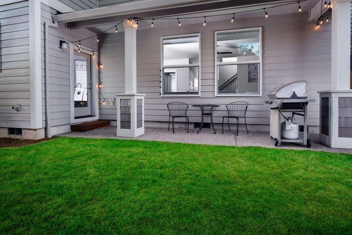 An inviting backyard setup with outdoor seating, a barbecue grill, and festive string lights creates the perfect atmosphere for social gatherings that spill outdoors.