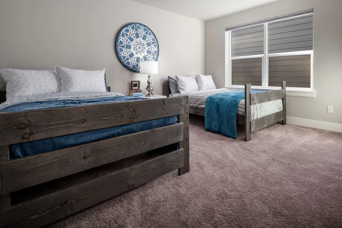 A serene bedroom with two beds, decorative wall art, and a nightstand with a lamp. Warm lighting and tasteful decor create a tranquil, intimate setting suitable for families or friends seeking privacy within the home.