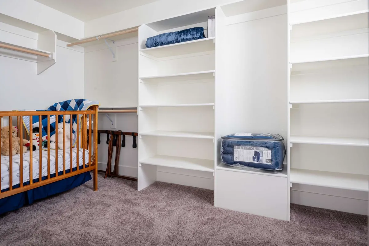 A dedicated nursery nook with a baby crib, shelves, and a selection of stuffed animals. The space feels warm, safe, and thoughtfully designed for the comfort of little ones and their caregivers.