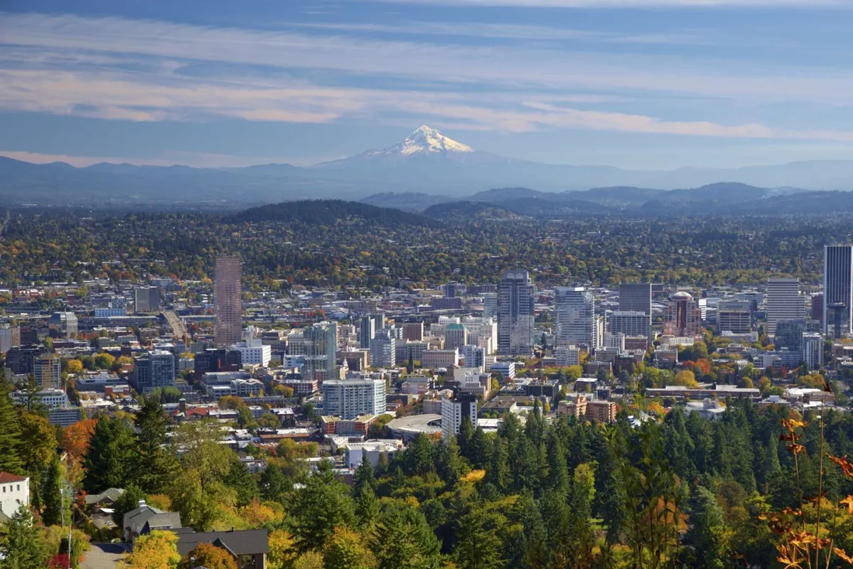 A sweeping view of Mount Hood, downtown Portland, and lush green treetops, evoking the beauty and variety of outdoor experiences available nearby. The scene alludes to local excursions and the proximity to natural and cultural attractions.